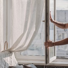 En man öppnar ett fönster för att släppa in frisk luft