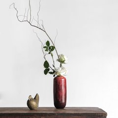 på ett mörkt träbord, en vinröd vas med vita blommor och en trädgren, i japansk stil